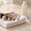 Clean makeup brushes on a white towel beside a bowl of water and gentle cleanser